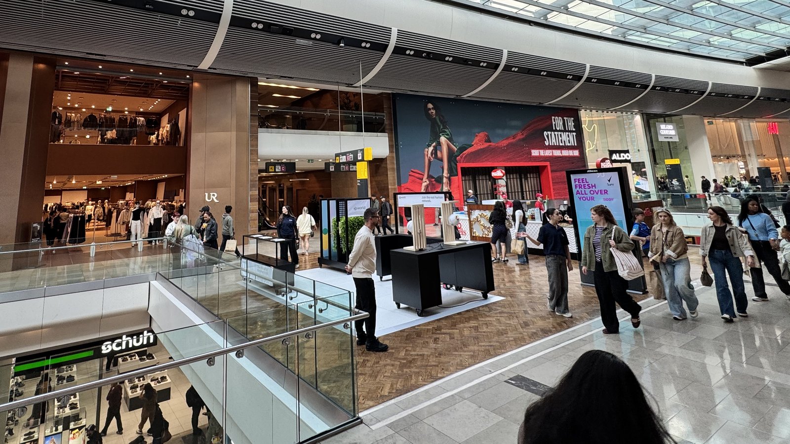 The kiosk on the upper floor of Westfield Stratford City with shoppers walking past.